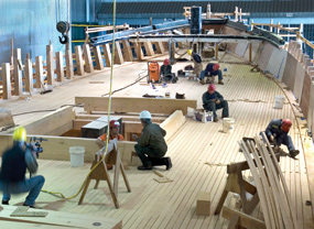 Shipyard workers on the main deck of the ship near the bow.