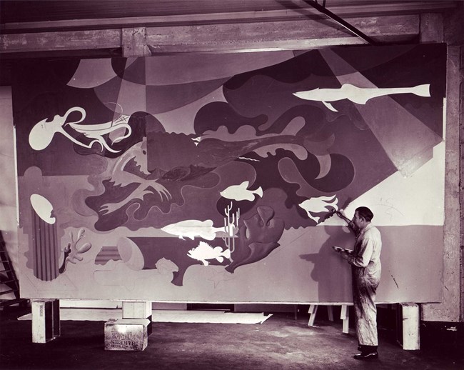 Historic photo of Hilaire Hiler in the process of painting the surreal murals