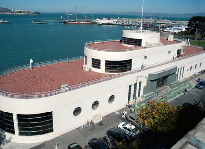 A large, ship-shaped building with a red roof on the SF Bay shoreline.