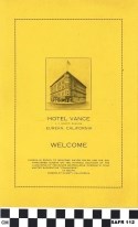 Yellow sheet of paper with black printing, under black and white image of hotel