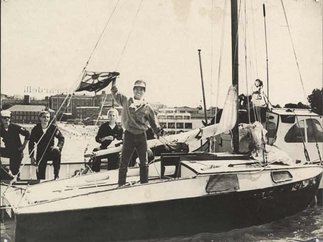 historical photograph of a young japanese man waving from a small sailing vessel