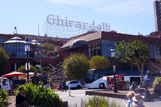 the brick buildings of Girardelli Square are teeming with visitors, beneath the large white Girardelli sign.