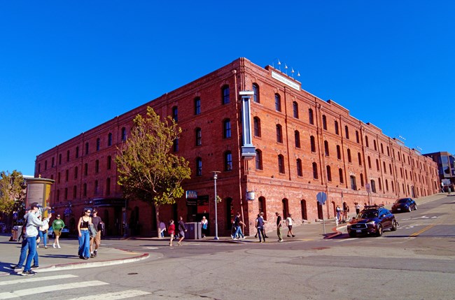 a large historic brick warehouse stands on a busy street corner