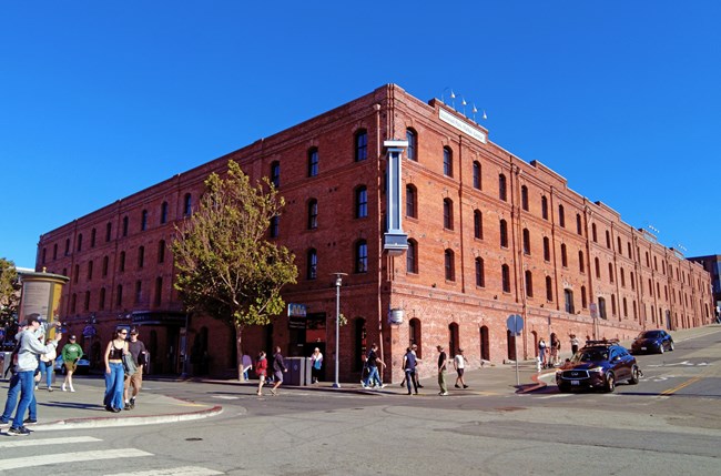 a large historic brick warehouse stands on a busy street corner