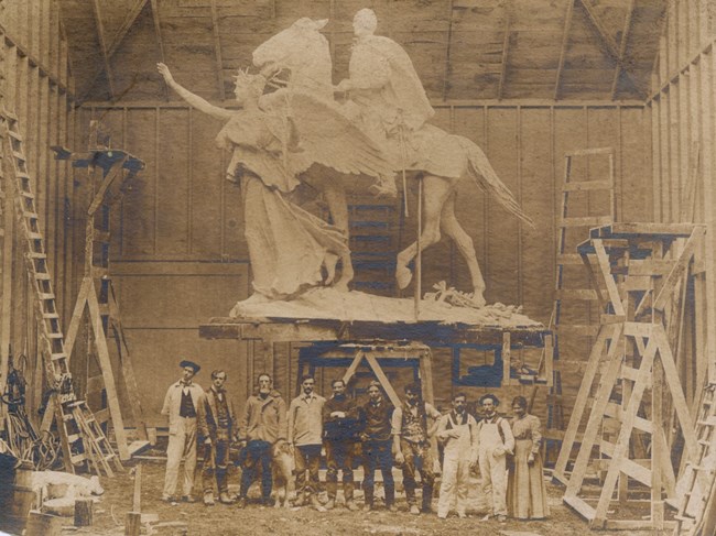 people standing in front of sculpture