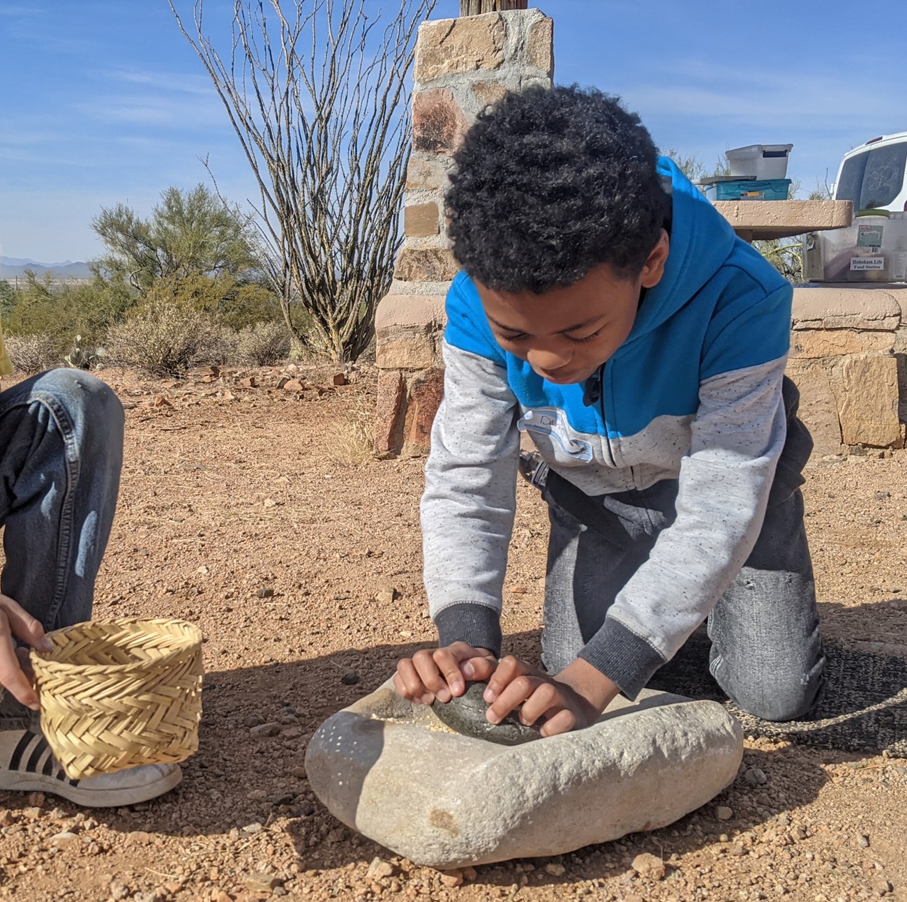 kid grinding corn on metate