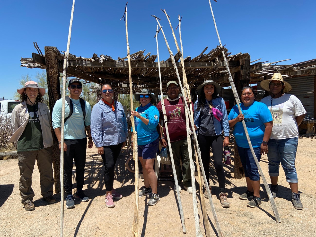 group of people with saguaro fruit gathering poles (kuipuds)
