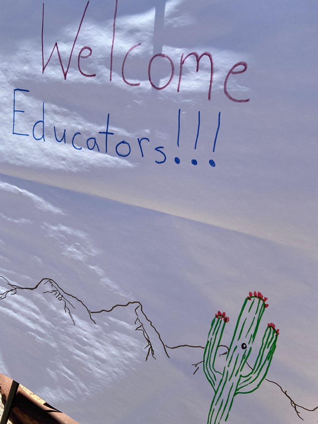 handwritten poster declaring "Welcome, Educators!" with illustrated desert landscape below