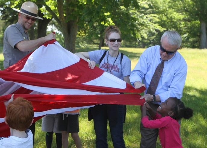 Students, teachers, and a park ranger fold a flag.