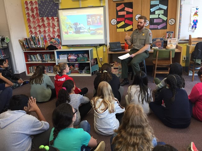 A park ranger speaks to a group of children in a classroom setting.