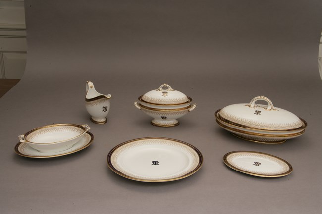 A china serving set with a gold trim design and the letters TR in the center.