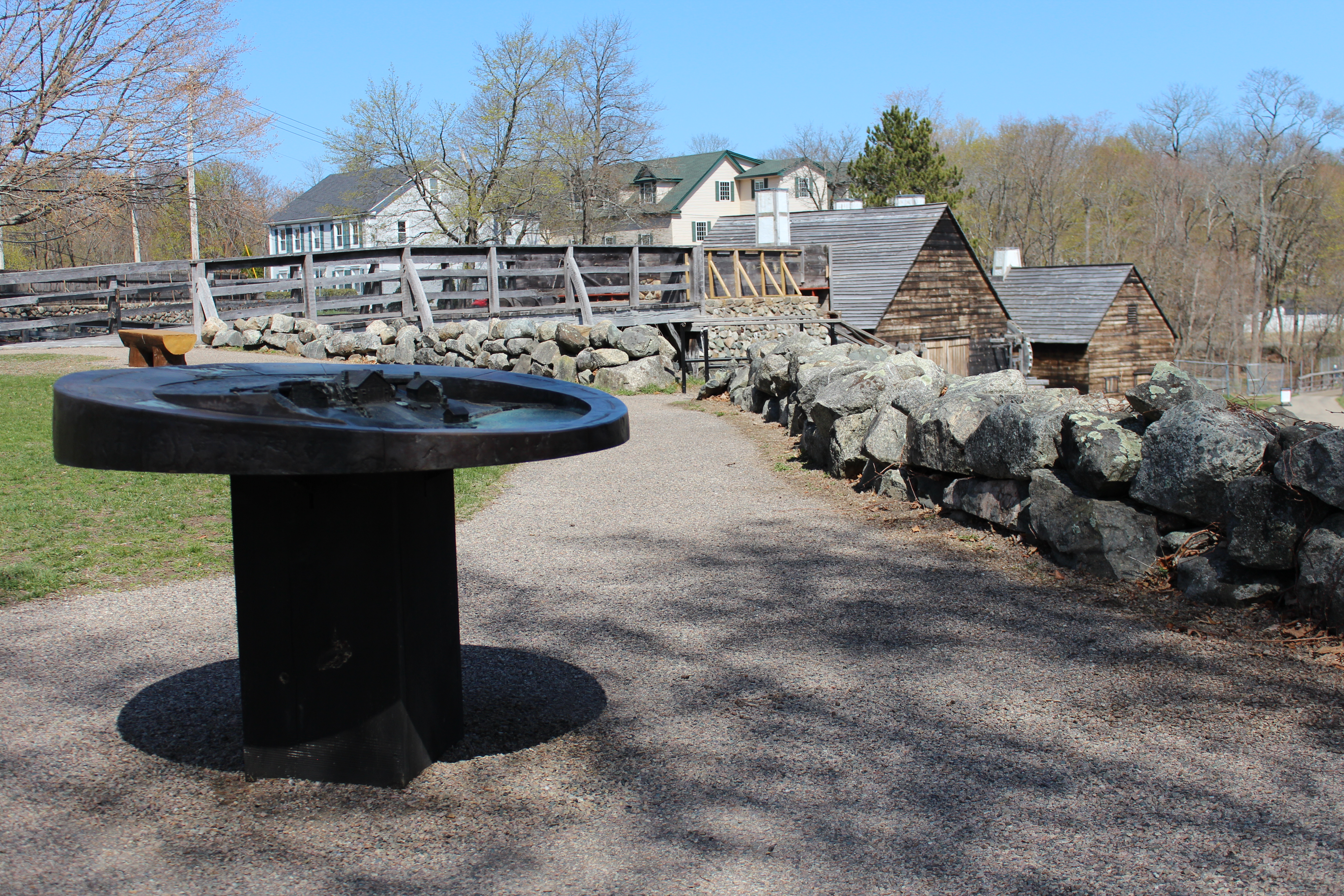 A metal tactile map by a walkway and stone wall
