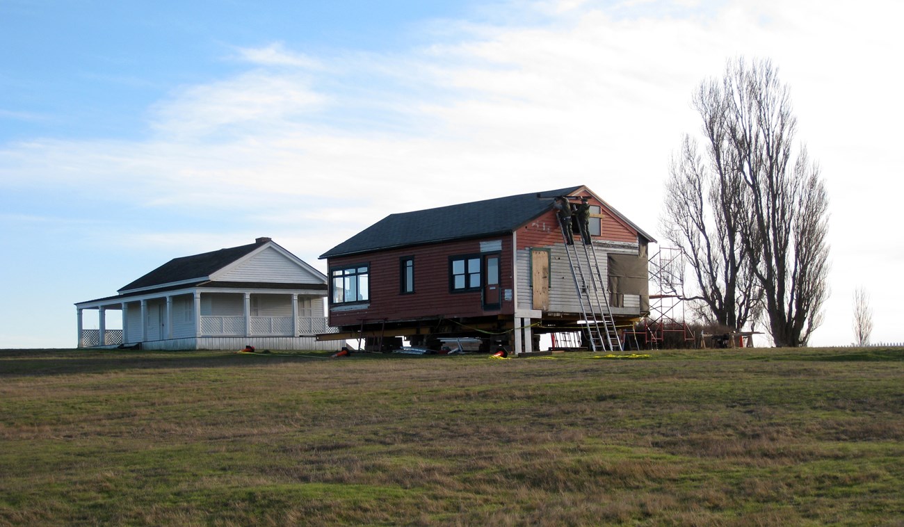 A building being moved and reconstructed next to a white historic building