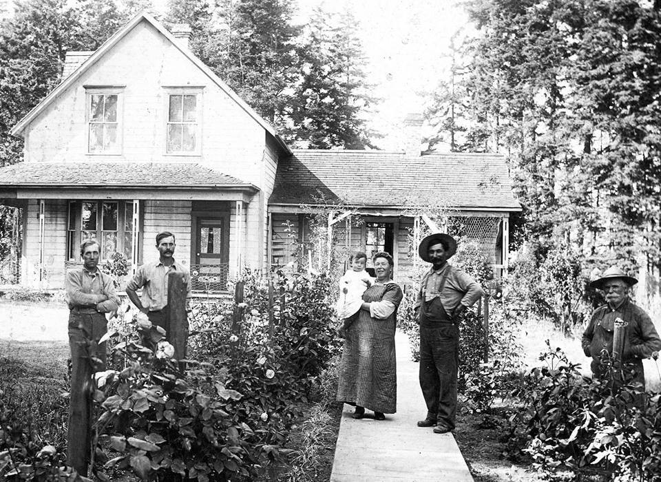 Historic photo of a family in front of a house with flowers along a path