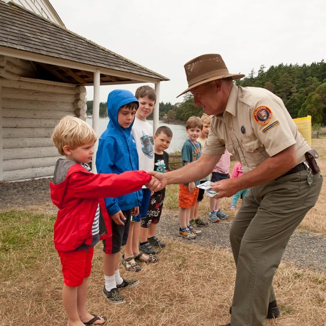 A park ranger shakes hands with children