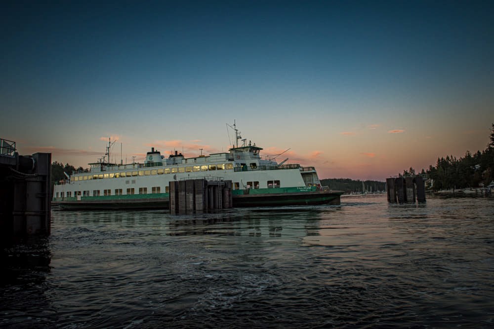 Photo of a ferry on the water from a dock at sunset