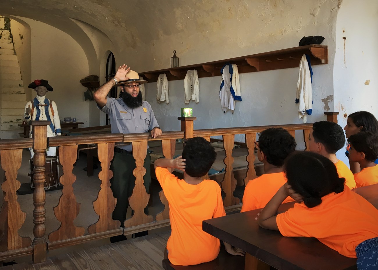 A group of students listens to a ranger talk at San Cristobal's Troop Quarters.