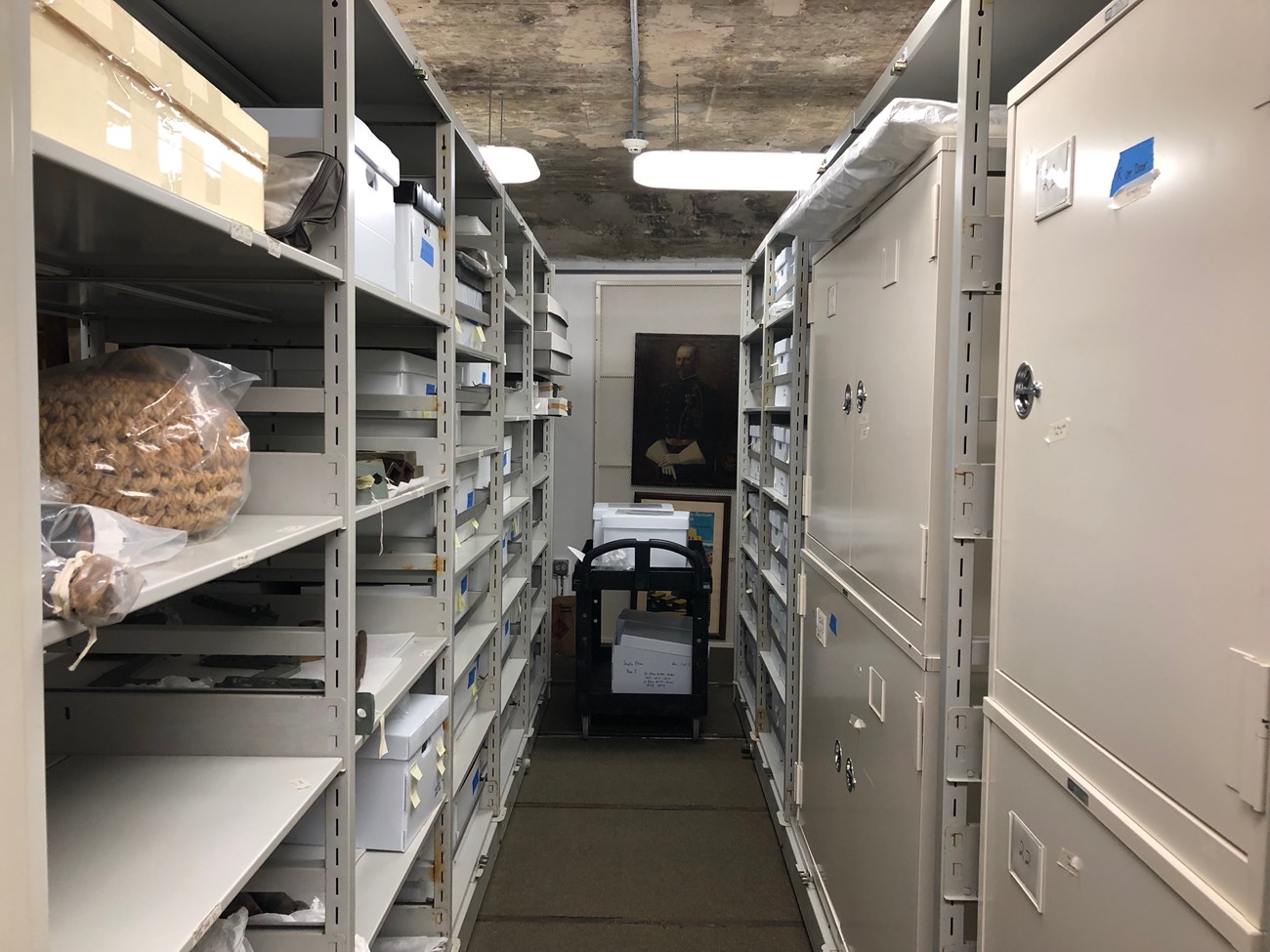 Open shelving with boxes and closed metal cabinets in a carpeted room