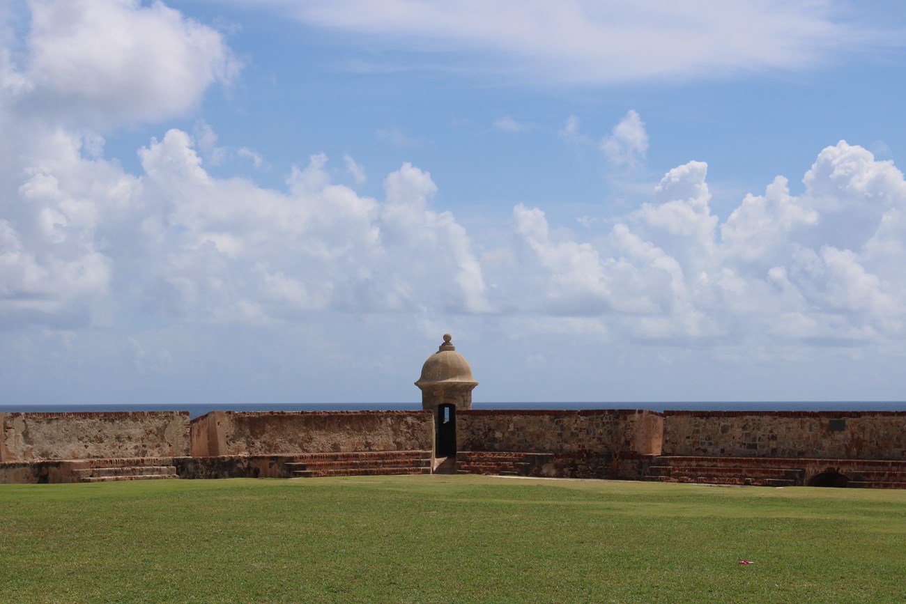 A sentry box stands at the point of a bastion looking out into the ocean.