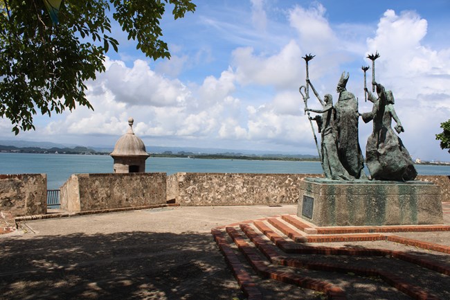 A plaza with a statue at the center and a sentry box looking out into the San Juan Bay