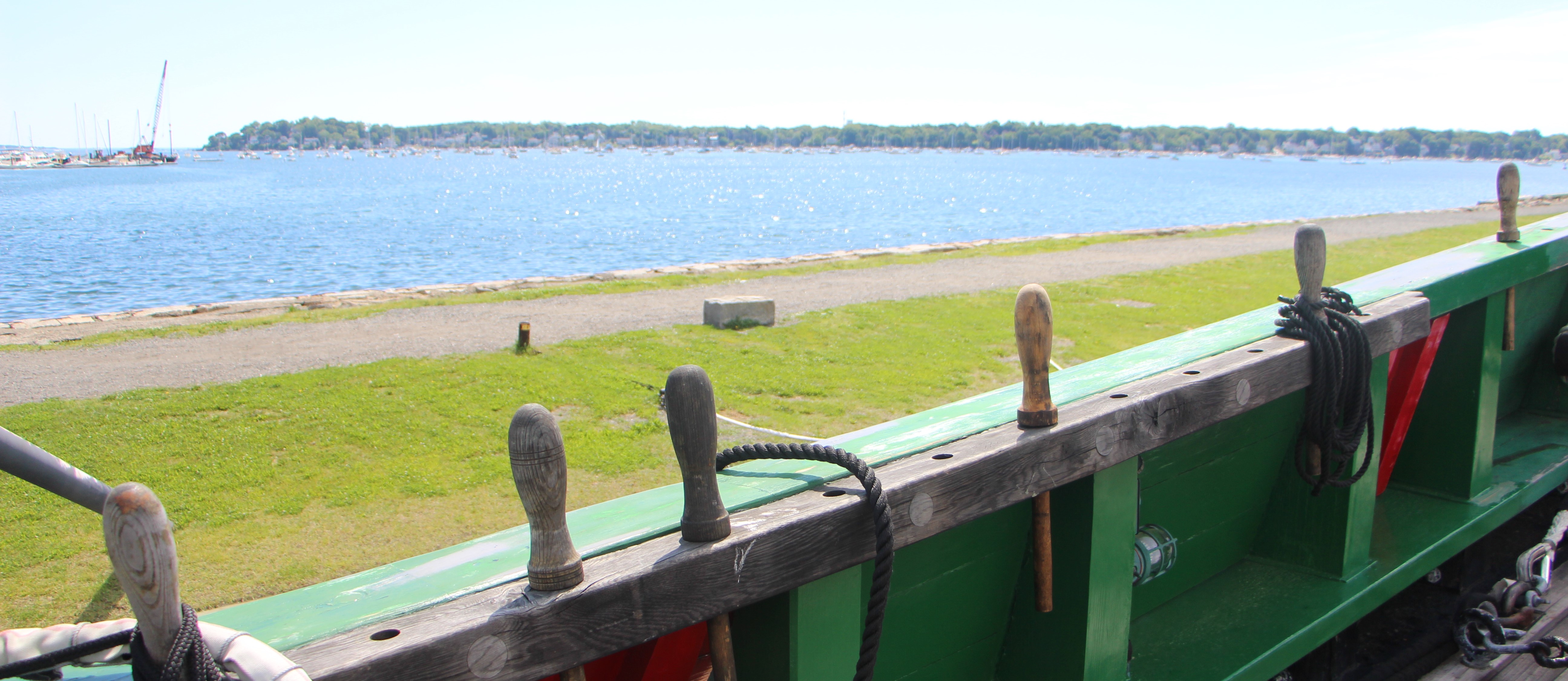 View from a ship looking out over a wharf extending into the water on a sunny day.