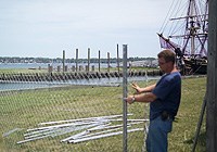 A workman assembles fencing on Central Wharf, with the replica tall ship Friendship in the background