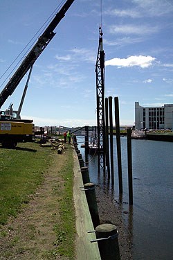 A pile driver placing supports for Pedrick Store House next to Derby Wharf