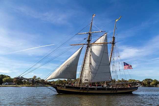 A wooden sailing ship traveling along the coast