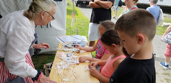 Three children learn about tying knots at a hands-on activity