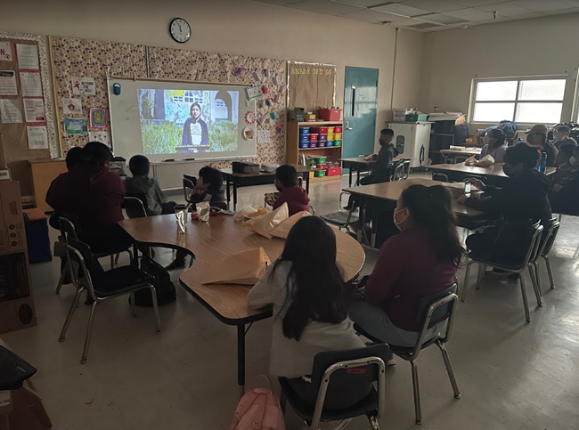 Students are gathered around screen participating in virtual program