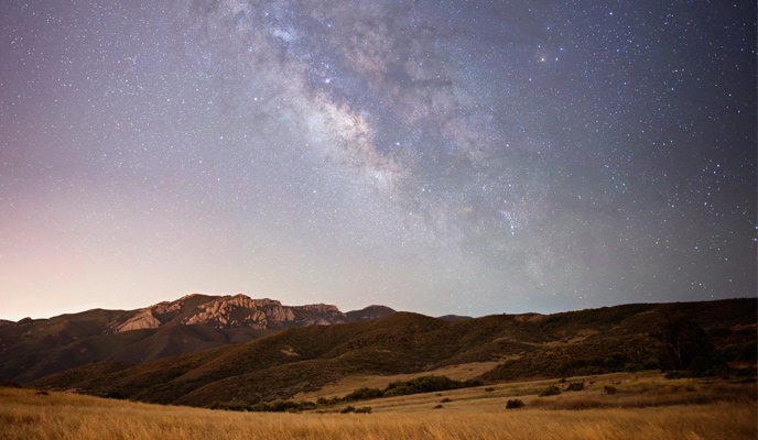 A view of the Milky Way over mountain ridges and open grassland