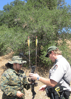 A ranger checks a hunter's weapon for safety.