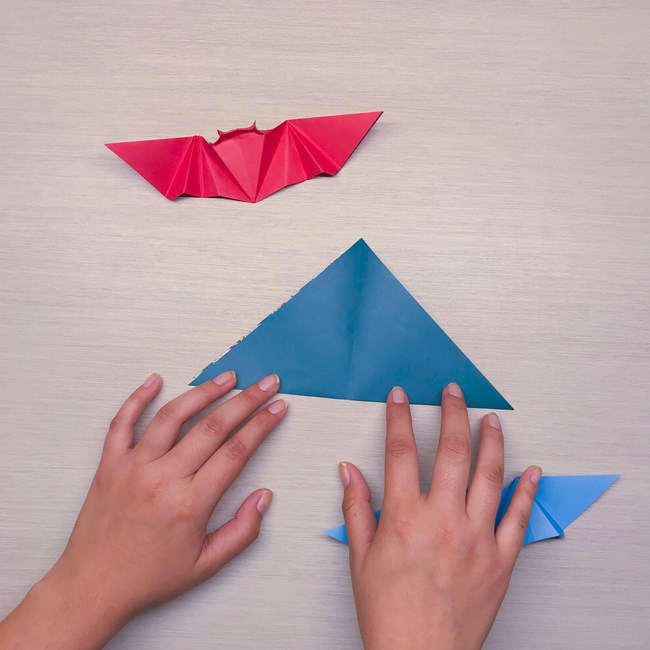 Two hands folding a triangle shape in half.