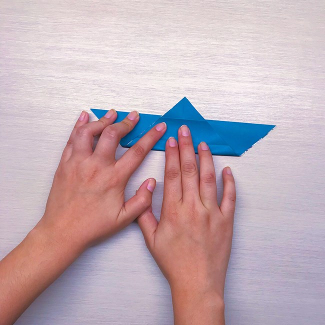 Hands folding origami paper.
