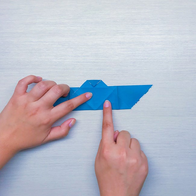 Two index fingers pointing to the center crease and a diagonal crease on the other side of the bat that will meet when folded.