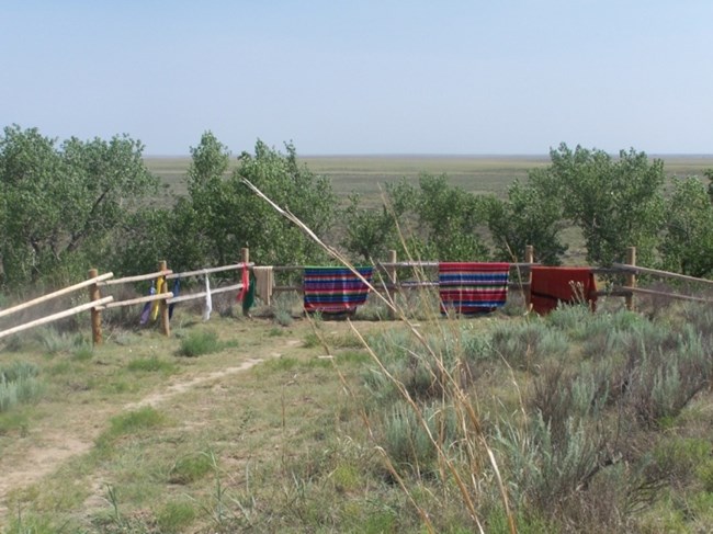 Tribal blankets over the fence on Monument Hill at Sand Creek Massacre NHS.