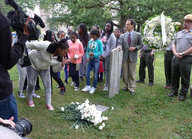 At a celebration of the renaming of two local schools after Rebecca and Benjamin Turner, local students lay flowers at the grave site of Rebecca Turner in the cemetery of St. Paul's Church.