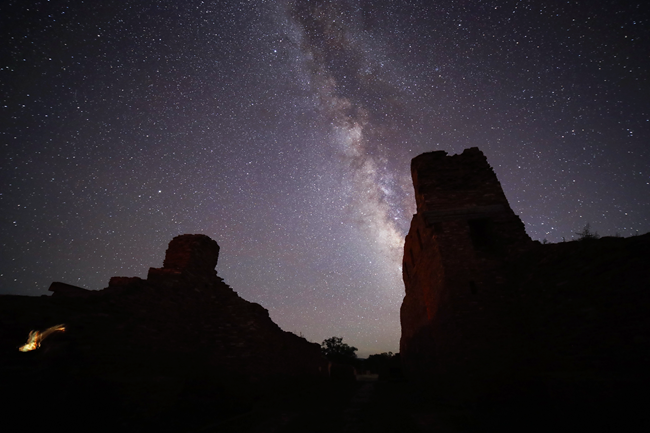 The Milky way galaxy with surrounding stars and church remnants in the foreground.