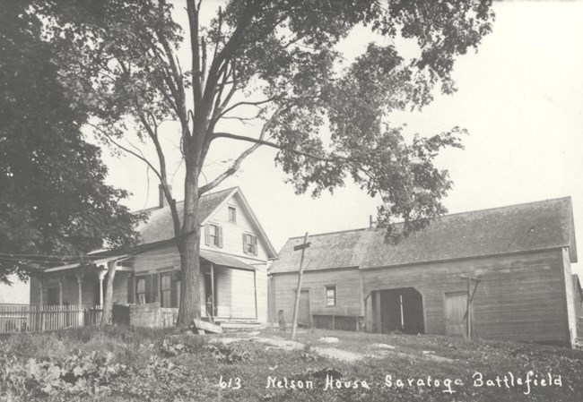 Black and white image of house and outbuildings circa 1920