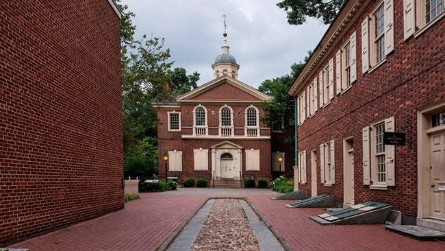 View down an alley way with cobblestones focusing on a large red brick building