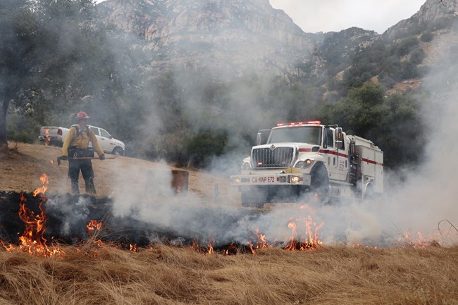 A crew member observes a grass fire next to wildland fire engine 72.