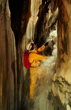 Caver stands in front of a waterfall in Lilburn Cave