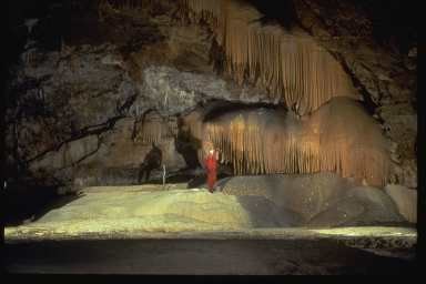 Caver stands beneath orange drapery in the Pumpkin Palace of the Hurricane Crawl Cave