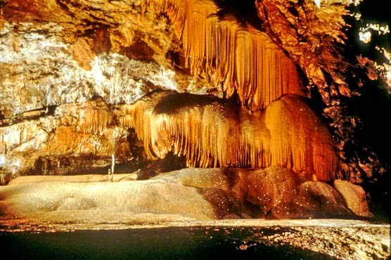 Curtains of orange drapery formations in Hurricane Crawl Cave in the parks