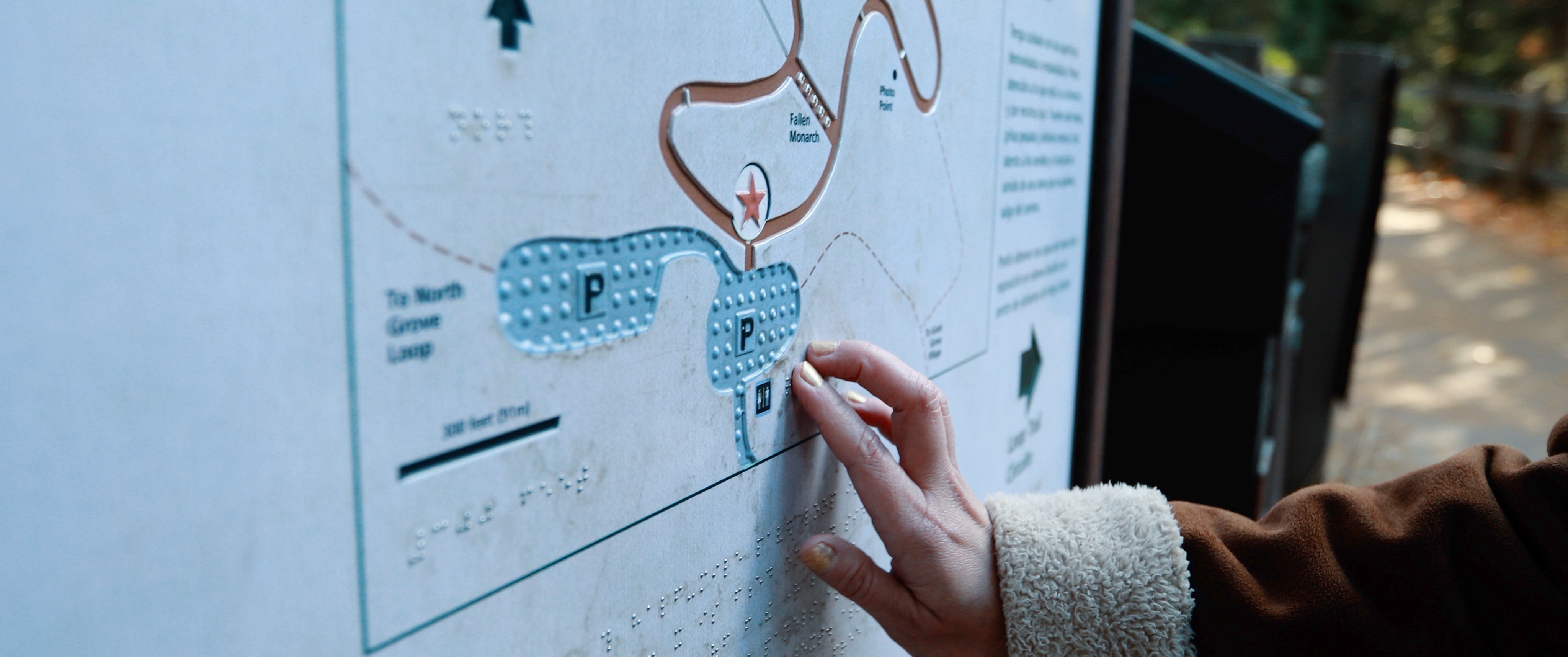 Close-up photo of a hand touching a surface with Braille and raised elements