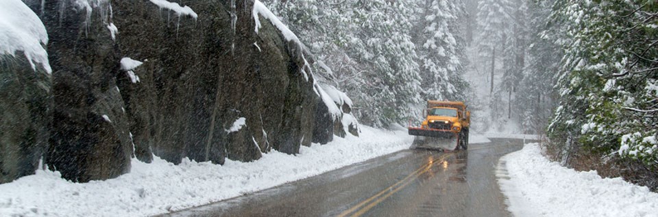 A snowplow drives along a snowy road