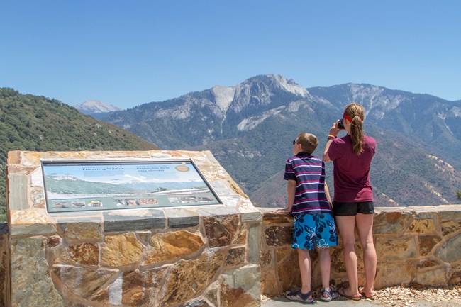 Two children look out on a view of granite mountains.
