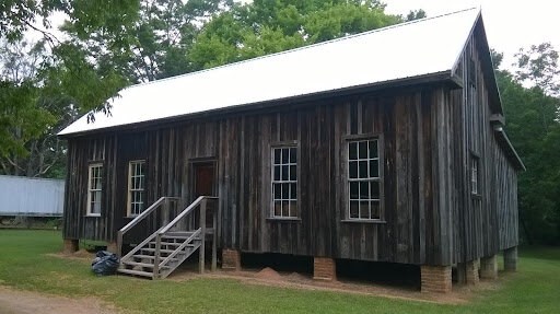 A simple raw wooden building atop cinder blocks.