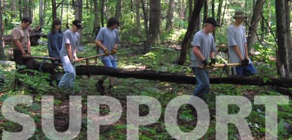 A group of volunteers move a fallen tree from a trail.