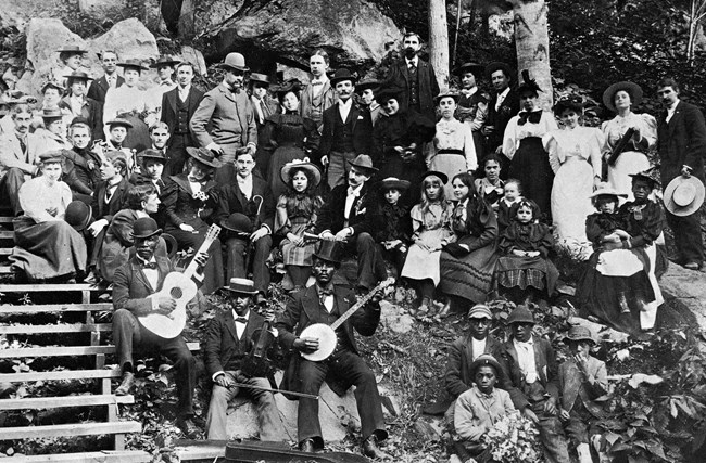 Black and white photo of many people sitting on a hillside.